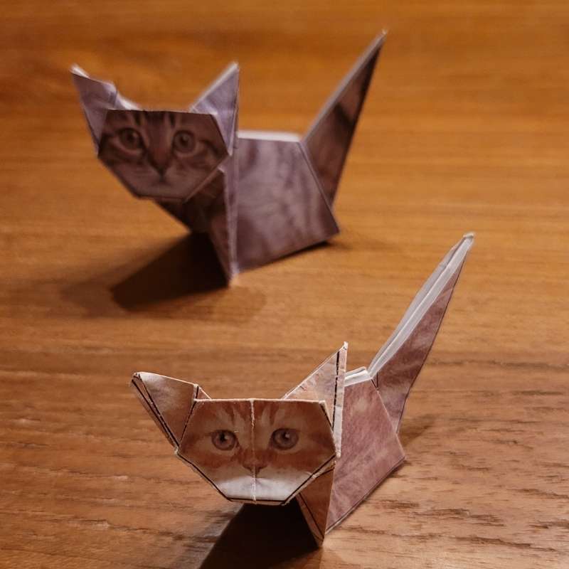 Zwei Origami-Katzen sitzen auf dem Tisch.