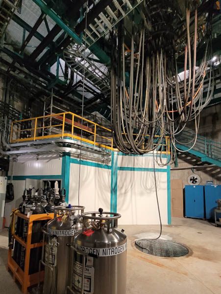 Technikraum im Vera C. Rubin Observatorium. Viele Schläuche und Kabel hängen von der Decke.